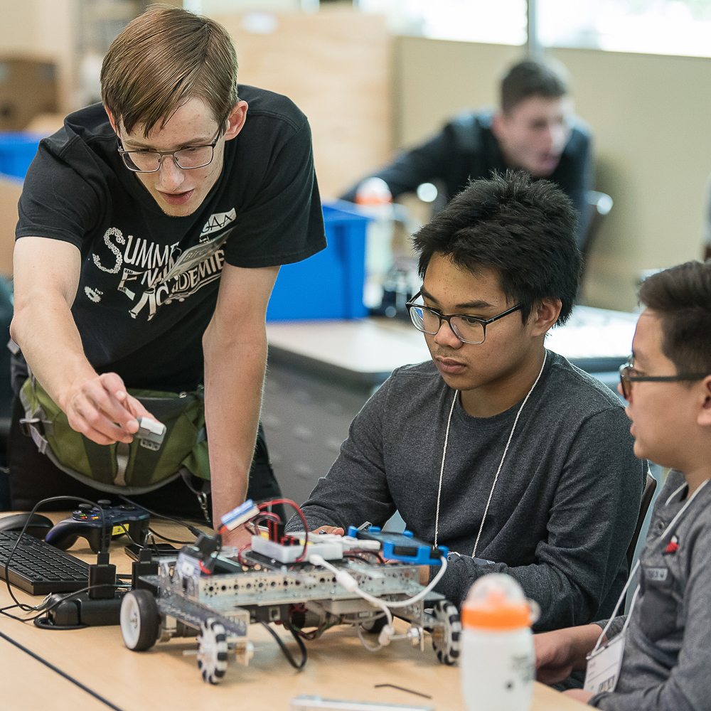 engineering student helping two kids build a robot