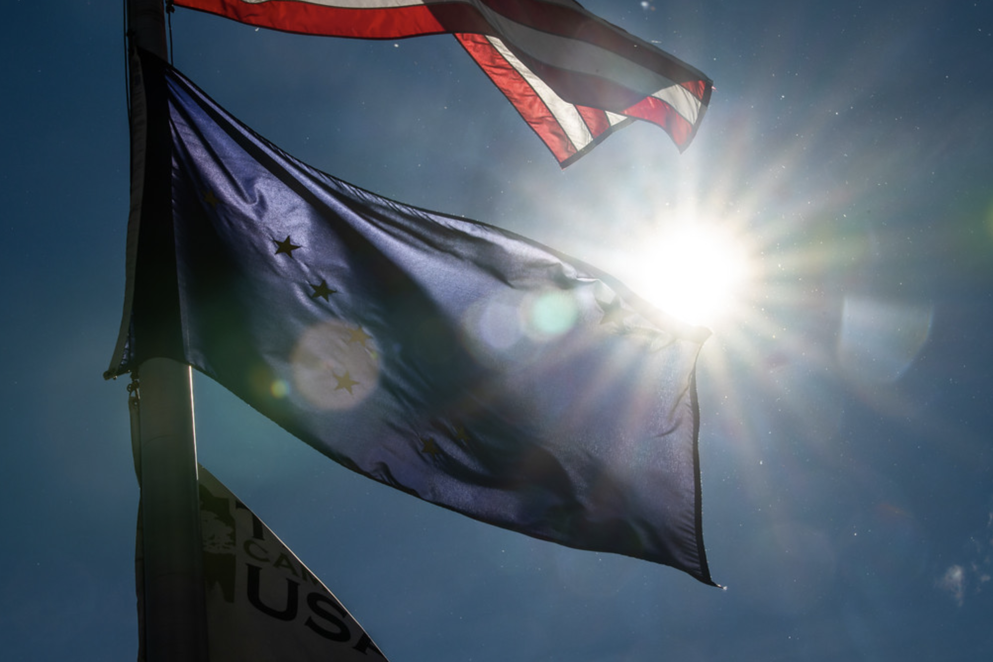 Bright sun over alaskan flag