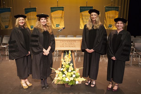Nursing graduates standing in black graduation cap and gown