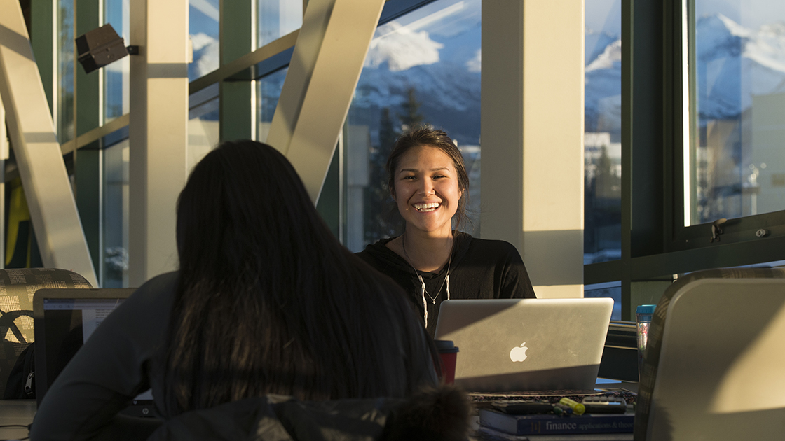 two students working at UAA, mountains in background