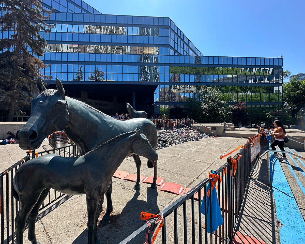 shoes piled on concrete straircase in front of metal horse sculptures