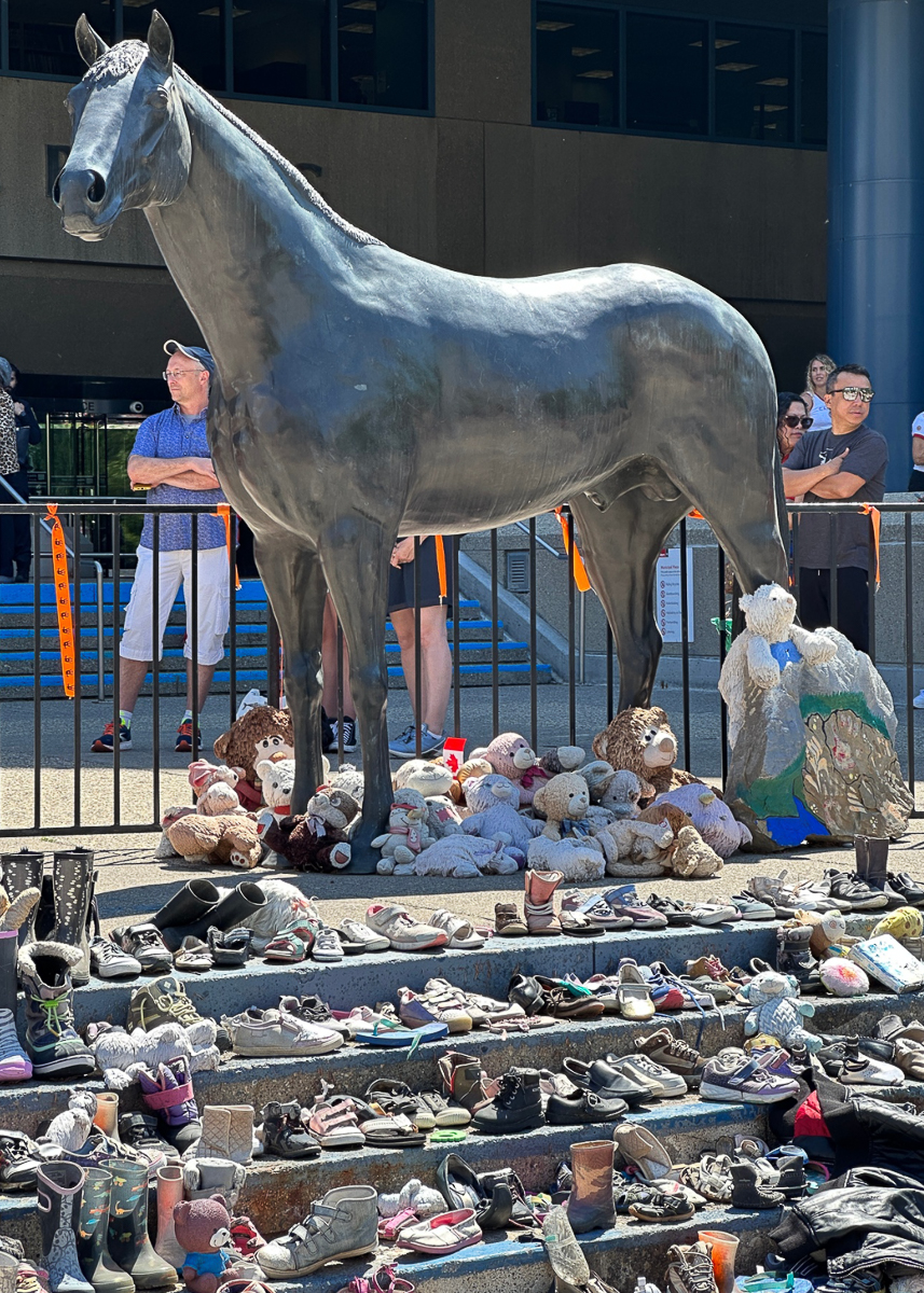 shoes piled on concrete straircase in front of metal horse sculpture