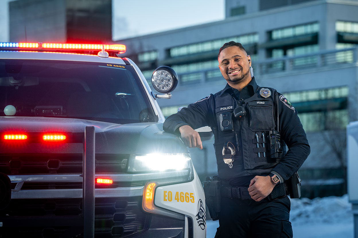 UPD Officer, Collin Hurd in front of his police car on UAA campus