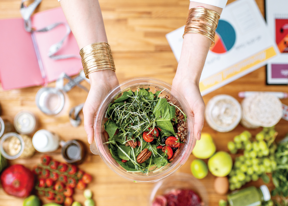 A person holding a bowl of salad.