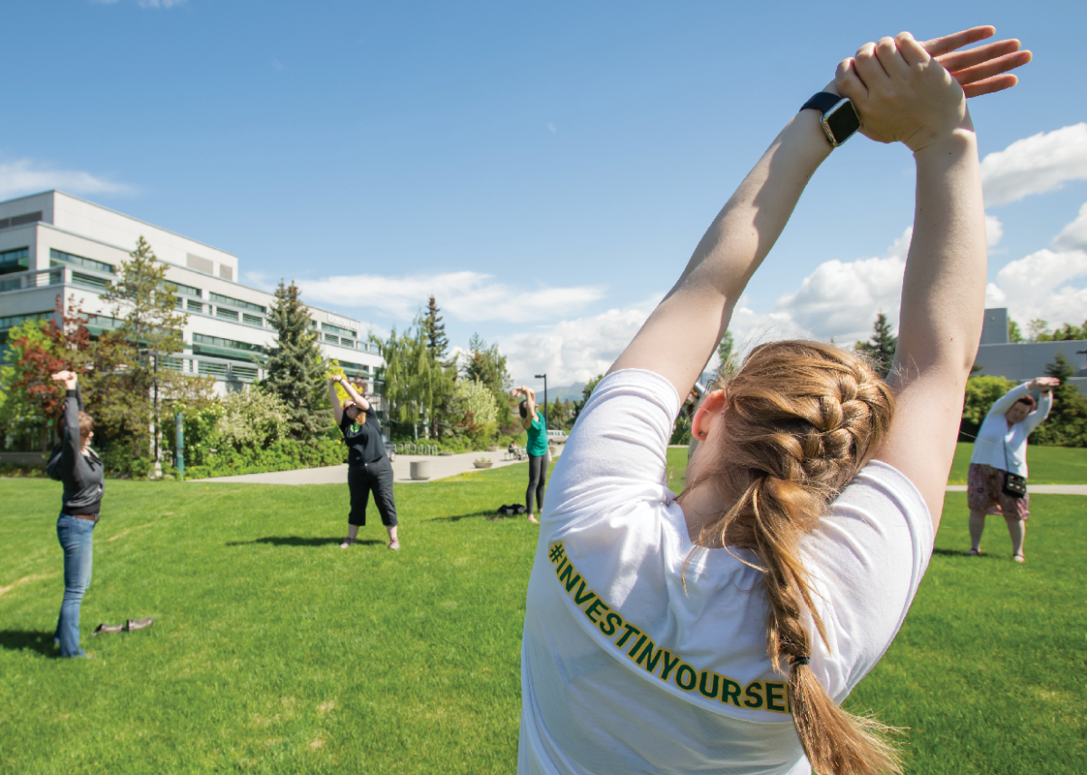 UAA students stretching on campus in the grass.