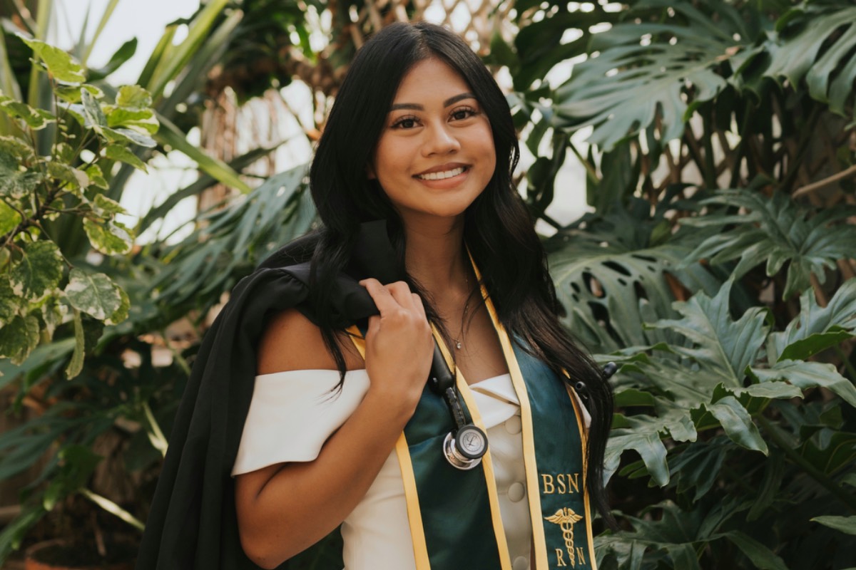 Kaycelyn Gajonera wearing graduation attire with greenhouse background