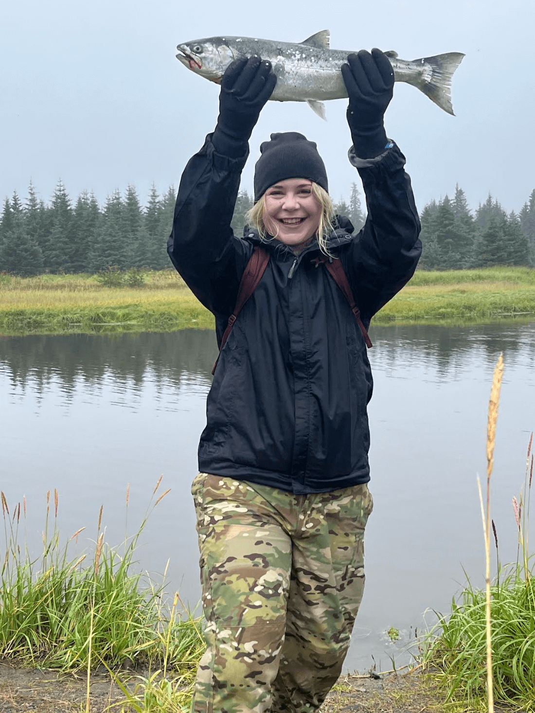 Kristen holds a fish above her head in Southcentral Alaska