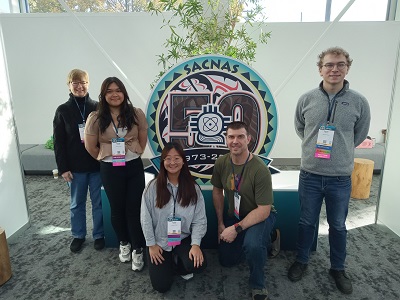 First Biomed U-RISE cohort poses in front of SACNAS conference sign