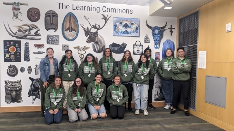 picture of students wearing green sweatshirts smiling