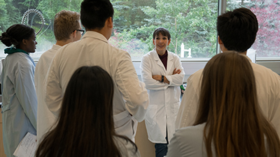 A group of students in lab coats gather in a circle