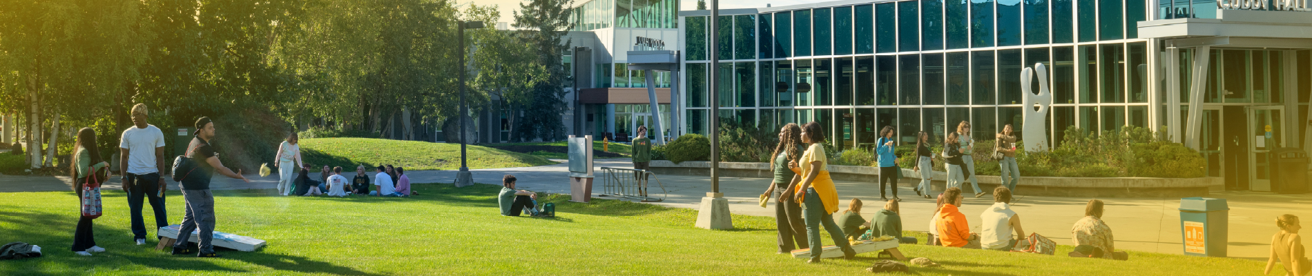 Students relaxing and playing cornhole on the Cuddy Quad on the UAA Anchorage campus.
