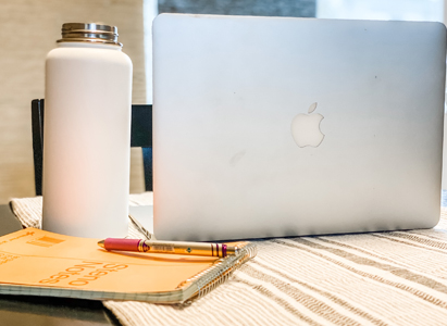 Remote workspace with laptop, water bottle and notepad