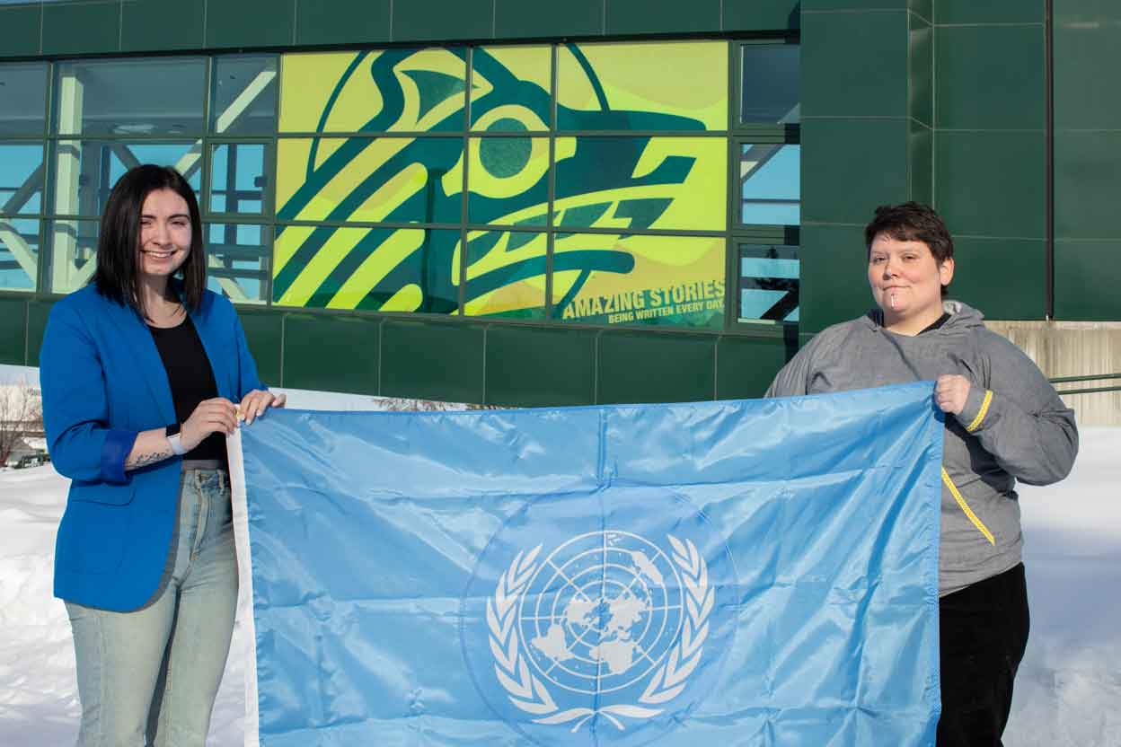 Abbie Lampman and Marya Halvorsen hold the flag of the United Nations.