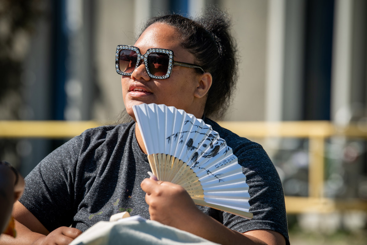 Tammalivis Salanoa from TRIO Student Services cools off with her "Thank You" fan from Korean Friendship Day during during the second of UAA's lunchtime Concerts in the Quad summer series.