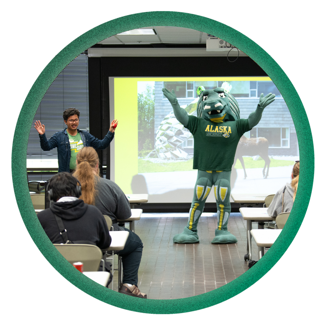 Orientation Leaders 2025 Spirit the Seawolf and one of the Orientation Leaders talking to incoming students during Orientation presentation.